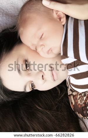 Young mother holding her sleeping baby boy