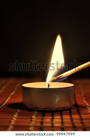 A match burning a tea candle