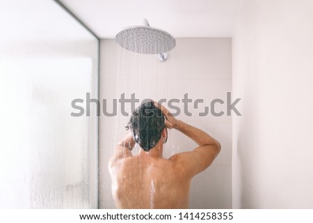 Man taking a shower washing hair with shampoo product under water falling from luxury rain shower head. Morning routine luxury hotel lifestyle guy showering. body care hygiene.