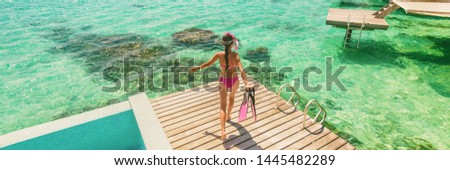 Luxury Bora Bora resort woman going snorkeling from overwater bungalow panoramic. Tahiti paradise destination vacation. 商業照片 © 