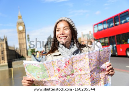 London tourist woman on Europe travel sightseeing holding map by Big Ben and red double decker bus. Tourism people concept with mixed race Asian girl smiling happy, Westminster Bridge, London, England