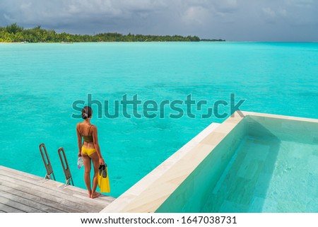 Hotel vacation woman swimming with snorkel mask and fins going snorkeling from private villa pool overwater bungalow. Travel luxury lifestyle in Bora Bora, Tahiti, French Polynesia. Watersport sport. 商業照片 © 
