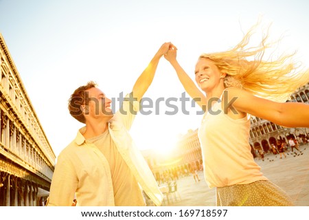 Dancing romantic couple in love in Venice, Italy on Piazza San Marco. Happy young couple having fun in dance on travel vacation on St Mark\'s Square. Beautiful blonde woman, handsome man in their 20s.