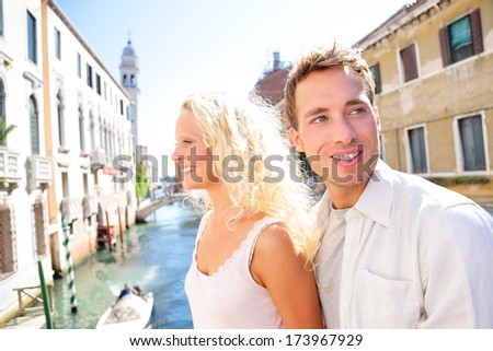 Young couple lifestyle walking in Venice on travel together. Happy couple on holidays or honeymoon having cute romantic vacation together in Venice on walk by Canal, Italy, Europe.
