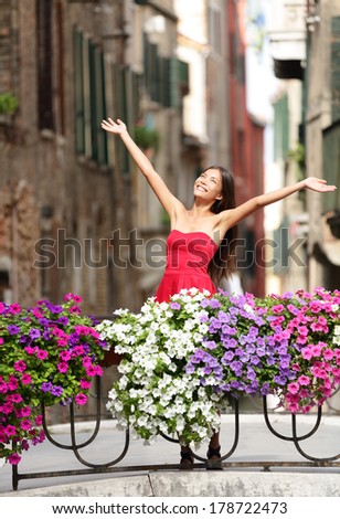 Woman happy in romantic Venice, Italy Girl standing in summer dress on bridge with flowers smiling joyful having fun. Beautiful multiracial Asian Caucasian young woman cheerful and vivacious.