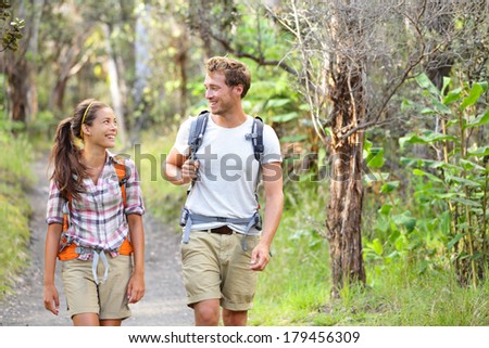 Hikers - hiking people walking happy in forest. Hiker couple laughing and smiling. Interracial couple, Caucasian man and Asian woman on Big Island, Hawaii, USA.