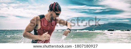 Triathlon competition swimmer man swimming looking at heart rate monitor tracker smartwatch. Panoramic banner. Outdoor sports.