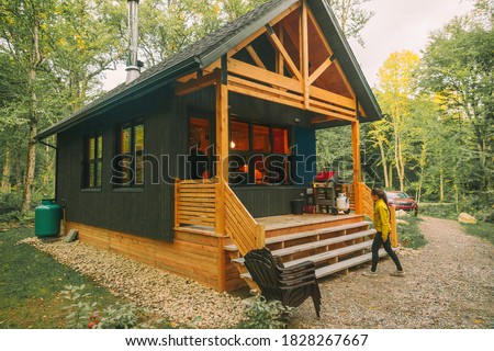 Vacation rental forest lodge countryside cabin by the lake for holidays in the wilderness. Woman entering her house home away from home.