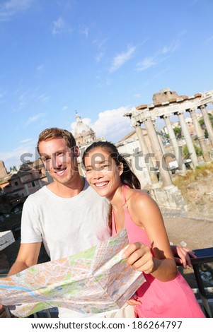 Tourists holding map by Roman Forum sightseeing on travel vacation in Rome, Italy. Happy tourist couple, man and woman traveling on holidays in Europe smiling happy. Interracial Asian Caucasian couple