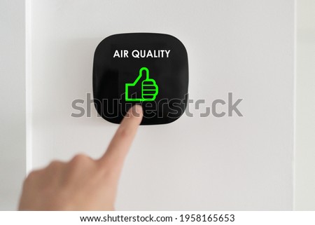 Good air quality indoor smart home domotic touchscreen system. air. Woman touching touchscreen checking air purifier filter at green level with thumbs up graphics.