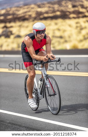 Triathlon time trial cycling triathlete man wearing aero bike helmet with visor biking on competition race day riding road bicycle vertical shot. Foto stock © 