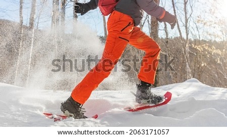 Winter sport outdoor exercise man running in snow in snowshoes having fun. Panoramic banner of snowing outside.