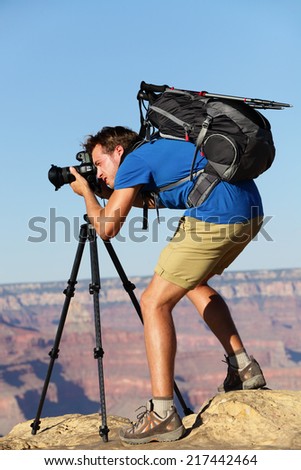 Photographer in Landscape nature in Grand Canyon taking picture photos with SLR camera and tripod during hike on south rim. Young man hiker enjoying landscape in Grand Canyon, Arizona, USA.