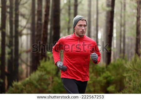 Running man in forest woods training and exercising for trail run marathon endurance race. Fitness healthy lifestyle concept with male athlete trail runner.