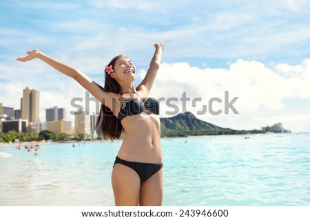 Beach woman in bikini happy and free on Waikiki, Oahu, Hawaii, USA. Girl on travel vacation holidays having fun on Hawaiian Waikiki beach with Diamond Head mountain. Asian Caucasian model.