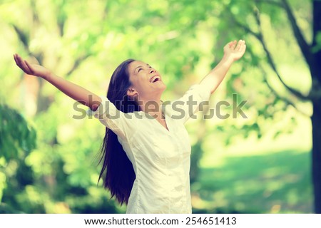 Freedom happy woman feeling alive and free in nature breathing clean and fresh air. Carefree young adult dancing in forest or park showing happiness with arms raised up. Spring allergies concept.