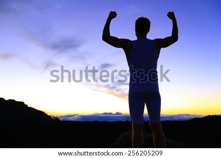 Strength - strong success fitness man flexing muscles showing power pose outside in silhouette at night. Muscular fit male fitness man celebrating success macho style.