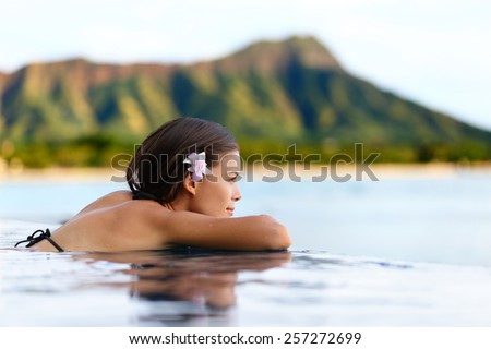 Infinity pool resort woman relaxing at sunset overlooking Waikiki beach in Honolulu city, Oahu island, Hawaii, USA. Wellness and relaxation concept for summer vacations.