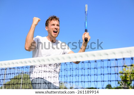 Tennis player celebrating victory. Winning cheering man happy in celebration of success and win. Fit male athlete winner on tennis court outdoors holding tennis racket in triumph by the net.