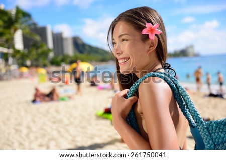 Asian tourist woman on vacation in Waikiki beach, Hawaii, USA. Pretty girl holding beach bag walking on famous touristic area in Honolulu city, Oahu, Hawaii, USA. Summer travel holiday concept.