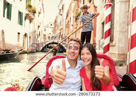Tourists happy couple traveling in Venice gondola giving thumbs up hand sign joyful on travel. Romantic young beautiful couple on vacation holidays sailing in venetian canal in gondole. Italy