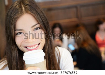 Portrait of young woman having coffee. Smiling beautiful mixed race Asian / Caucasian female is with disposable cup. She is in coffee shop.