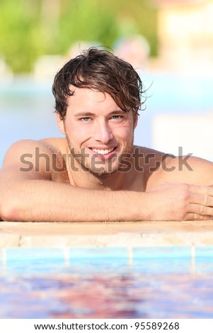 Man in swimming pool during vacation in holiday resort. Handsome male model enjoying sunny holidays under the sun. Young Caucasian man in his twenties.
