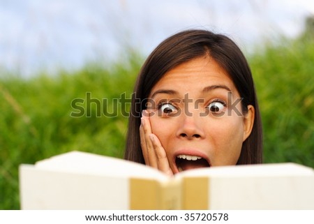 young beautiful woman surprised by the story she is reading in her book.