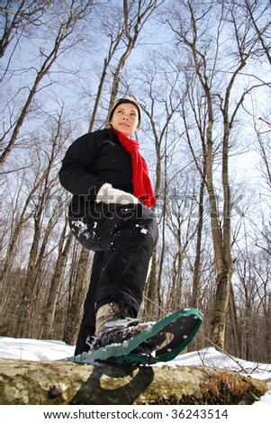 Woman winter hiking with snowshoes in a forest in Quebec, Canada.