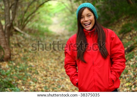 Autumn woman excited and laughing. Beautiful woman walking in the forest on a fall day.
