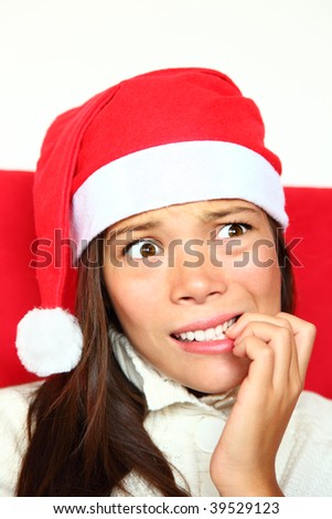 Christmas woman with santa hat nervous biting nails. Beautiful mixed asian / caucasian model.