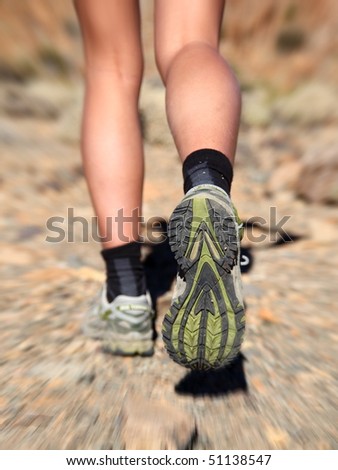 Woman running on trail in desert. Zoom motion blurred closeup shoes of woman trail running in desert.