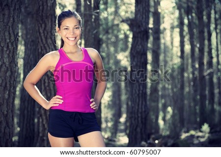 Woman runner in forest. Portrait of female runner taking a break from running in beautiful forest with lots of mood / atmosphere and copy space. Beautiful young female athlete.