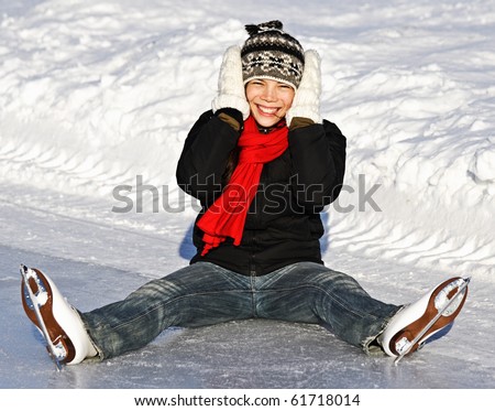 Winter Ice skating Girl having fun on ice skate rink outdoors. Cute photo of young smiling asian woman sitting on the ice. From Quebec City, Canada.