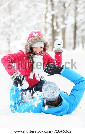 Winter couple snowball fight. Young couple having fun in snow outside. young couple in their twenties.
