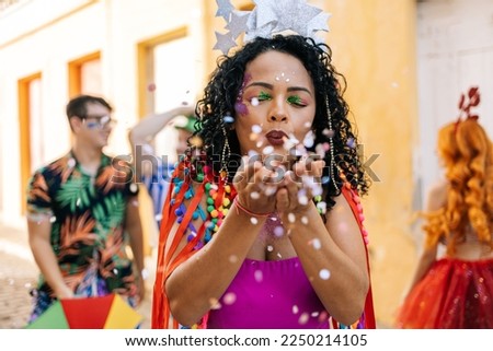 Brazilian Carnival. Young woman enjoying the carnival party blowing confetti 商業照片 © 