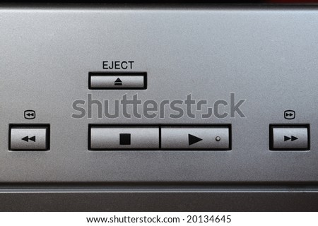 Macro photograph of play, stop, eject, rewind and fast forward buttons on a silver plated device