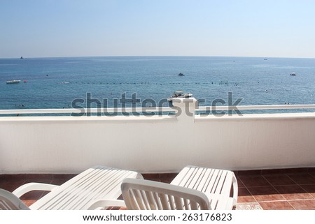 Two white lounge chairs on terrace with sea view