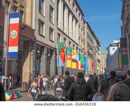 MILAN, ITALY - MARCH 28, 2015: Tourists walking by the flags from all countries of the world on show in Milan city centre as part of the Expo Milano 2015 international exhibition