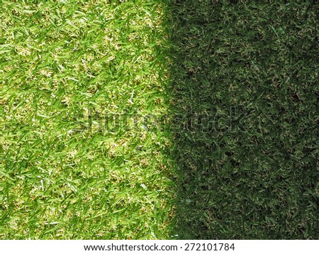 Green artificial synthetic grass meadow texture useful as a background - sunny and shadow spot