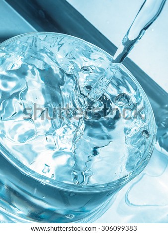 Close-up macro of water flow in a glass - cool cold tone