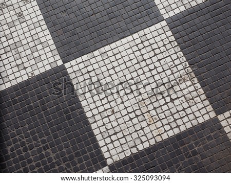Checkered black and white mosaic stone pavement useful as a background