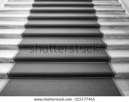 Red carpet on a stairway used to mark the route taken by heads of state, vips and celebrities on ceremonial and formal occasions or events in black and white