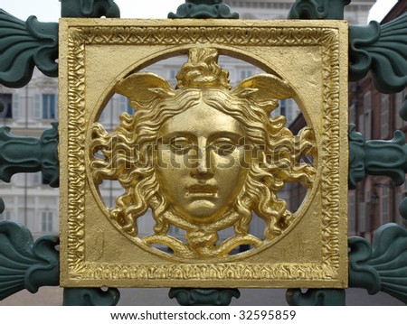 Ancient golden baroque mask on the fence of Palazzo Reale, Turin, Italy