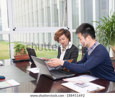Image of two young businessmen using laptop at meeting