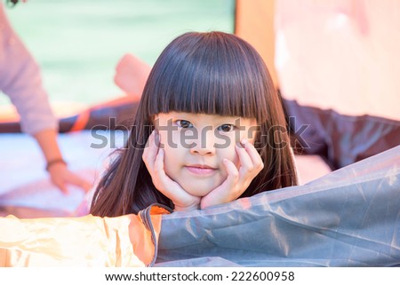 The little girl lying indoor of camping tent smiling