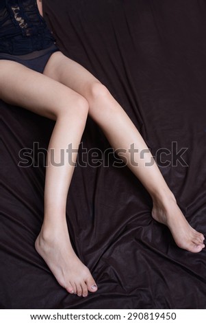 Sexy woman  smooth long legs posing  lying isolated on a black background