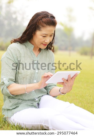 elderly woman use tablet computers.Sitting in the garden on the lawn