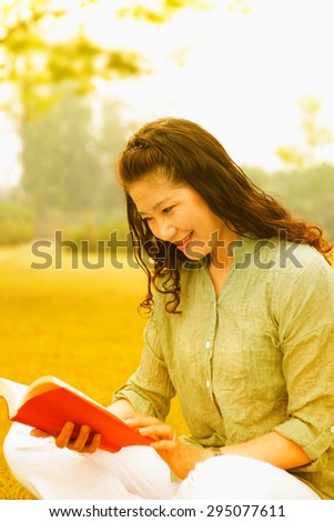 Beautiful old woman reading a book. On the garden lawn