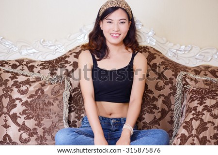 Happy Asian girl sitting on the sofa in the interior